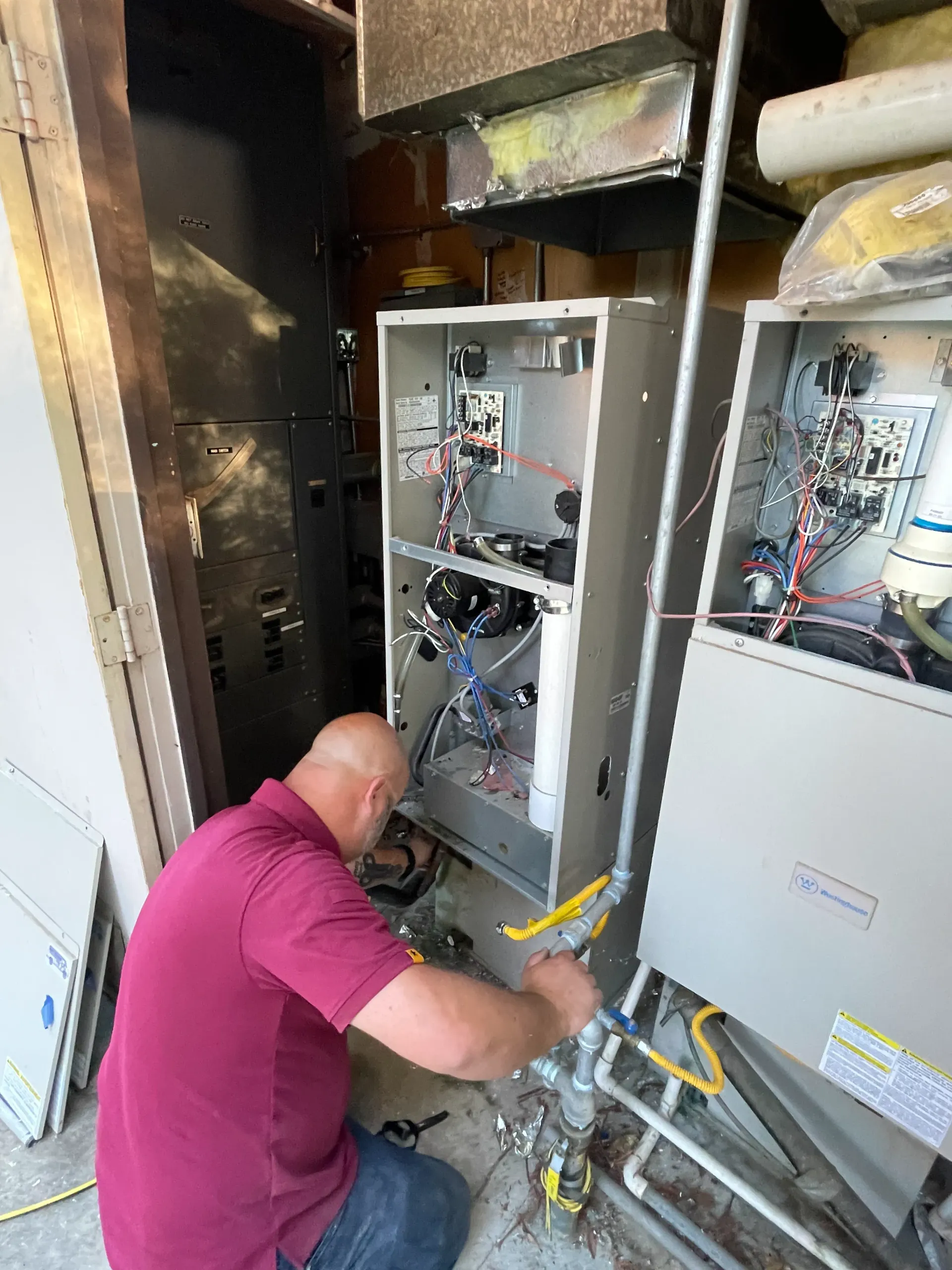 A man is working on a heating system in a garage.