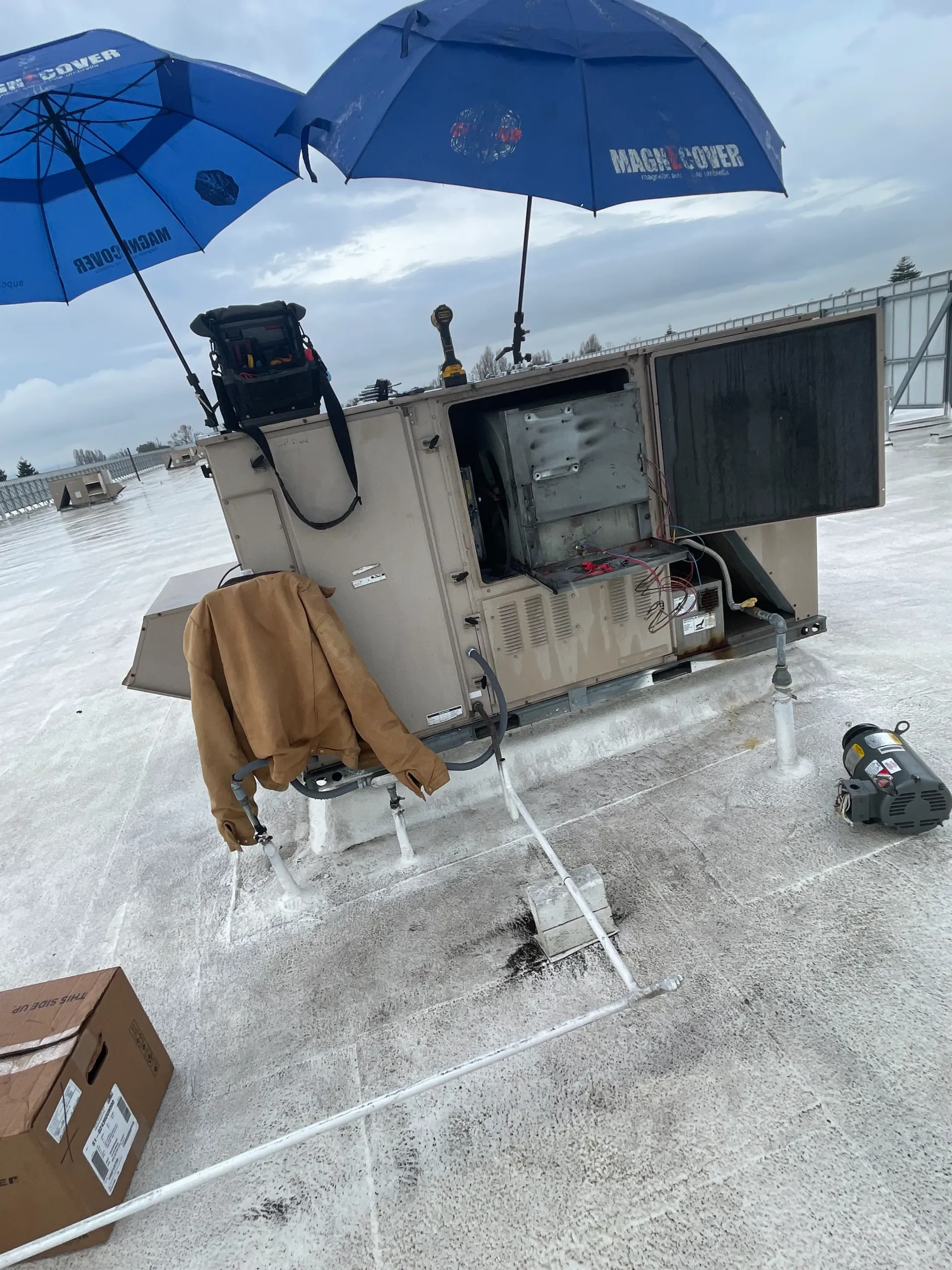A blue umbrella is sitting on top of a machine on a roof.