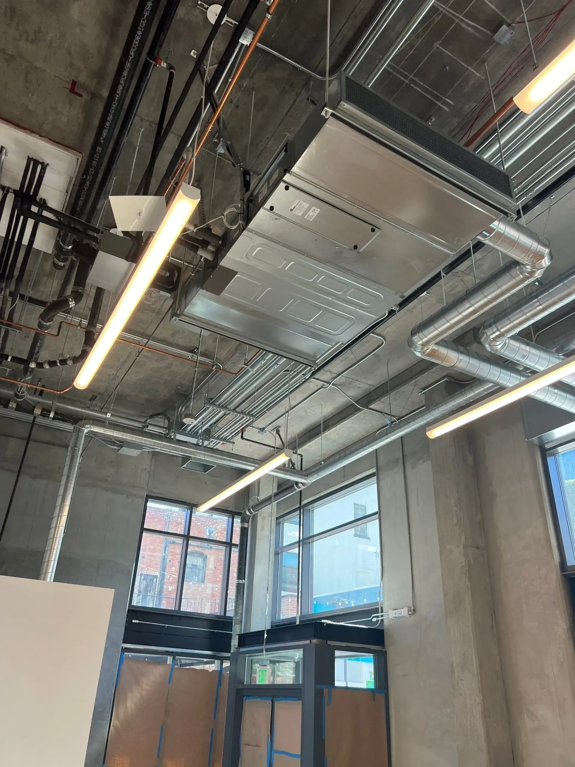 A room with a lot of pipes and lights hanging from the ceiling.