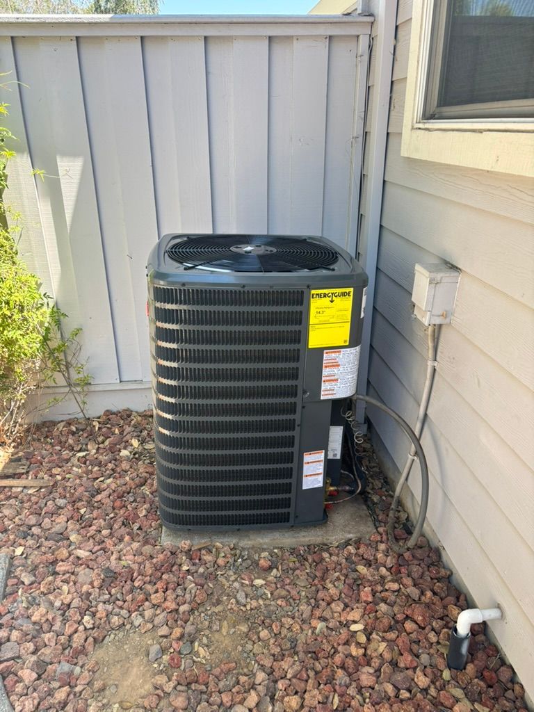 An air conditioner is sitting on the side of a house.