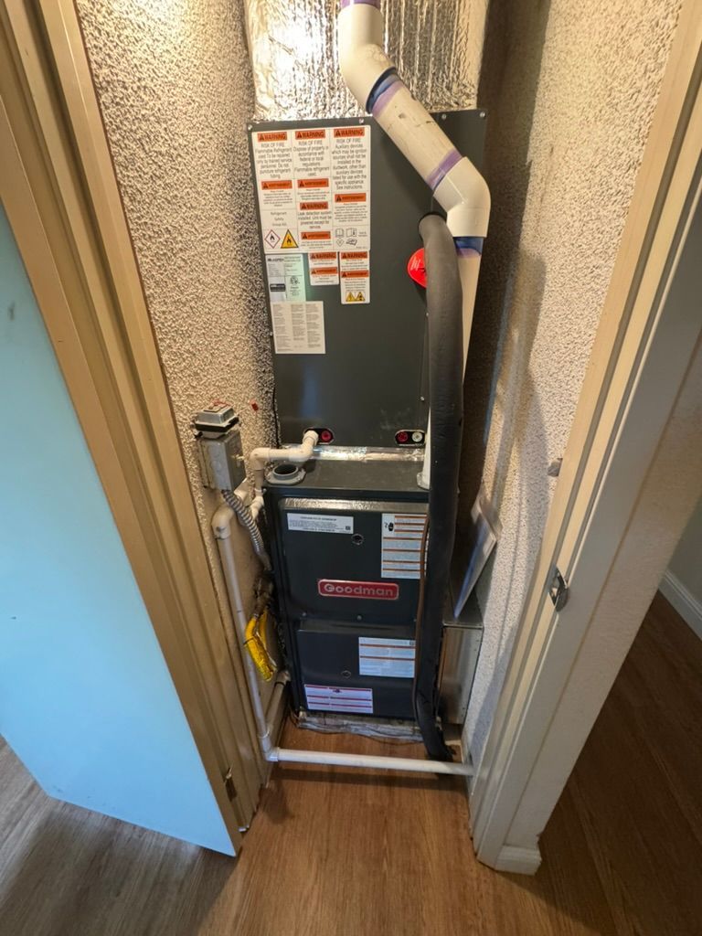 An air conditioner is sitting in a closet next to a door.