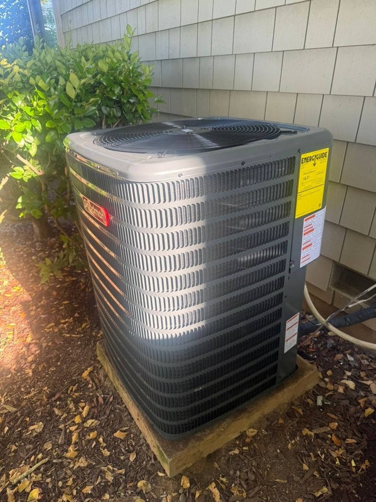 A large air conditioner is sitting outside of a house.