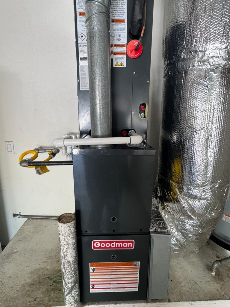 A goodman air conditioner is sitting on the floor in a room.