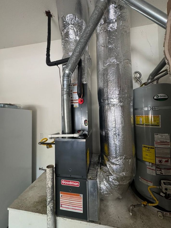 A person is cleaning a furnace with a vacuum cleaner.