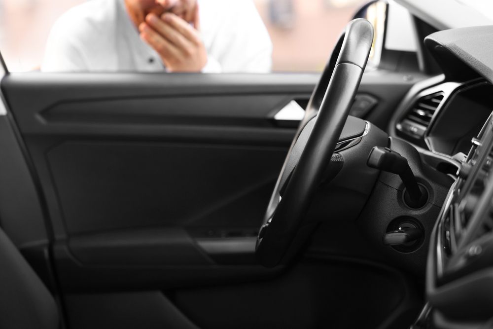 A man is talking on a cell phone in a car.