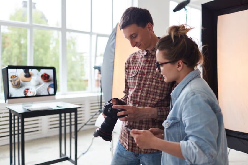 A man and a woman are looking at a camera in a photo studio.