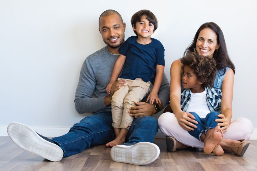 A family is sitting on the floor posing for a picture.