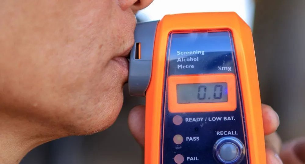 A Person Using A Breathalyzer — Cairns Traffic Lawyers In Cairns City, QLD