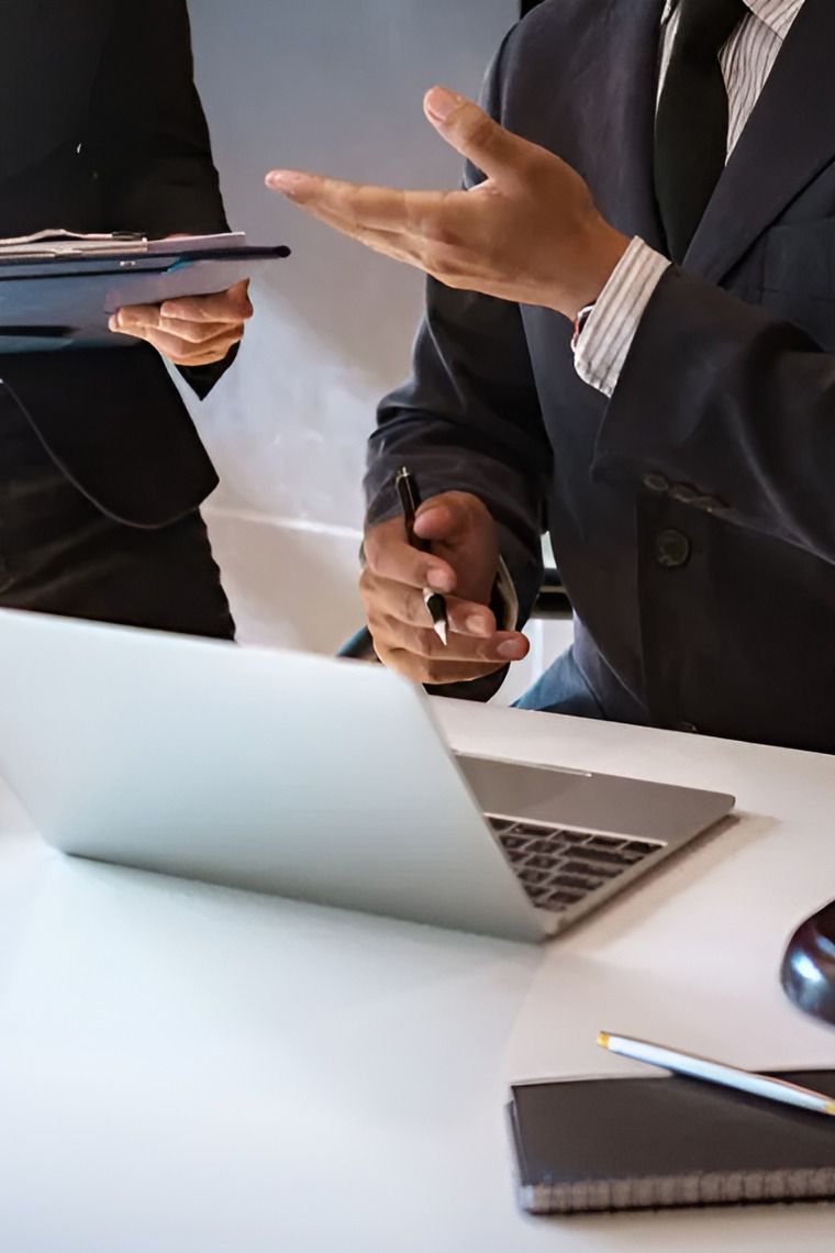 A Man And A Woman Are Sitting At A Desk With A Laptop — Cairns Traffic Lawyers In Palm Cove, QLD