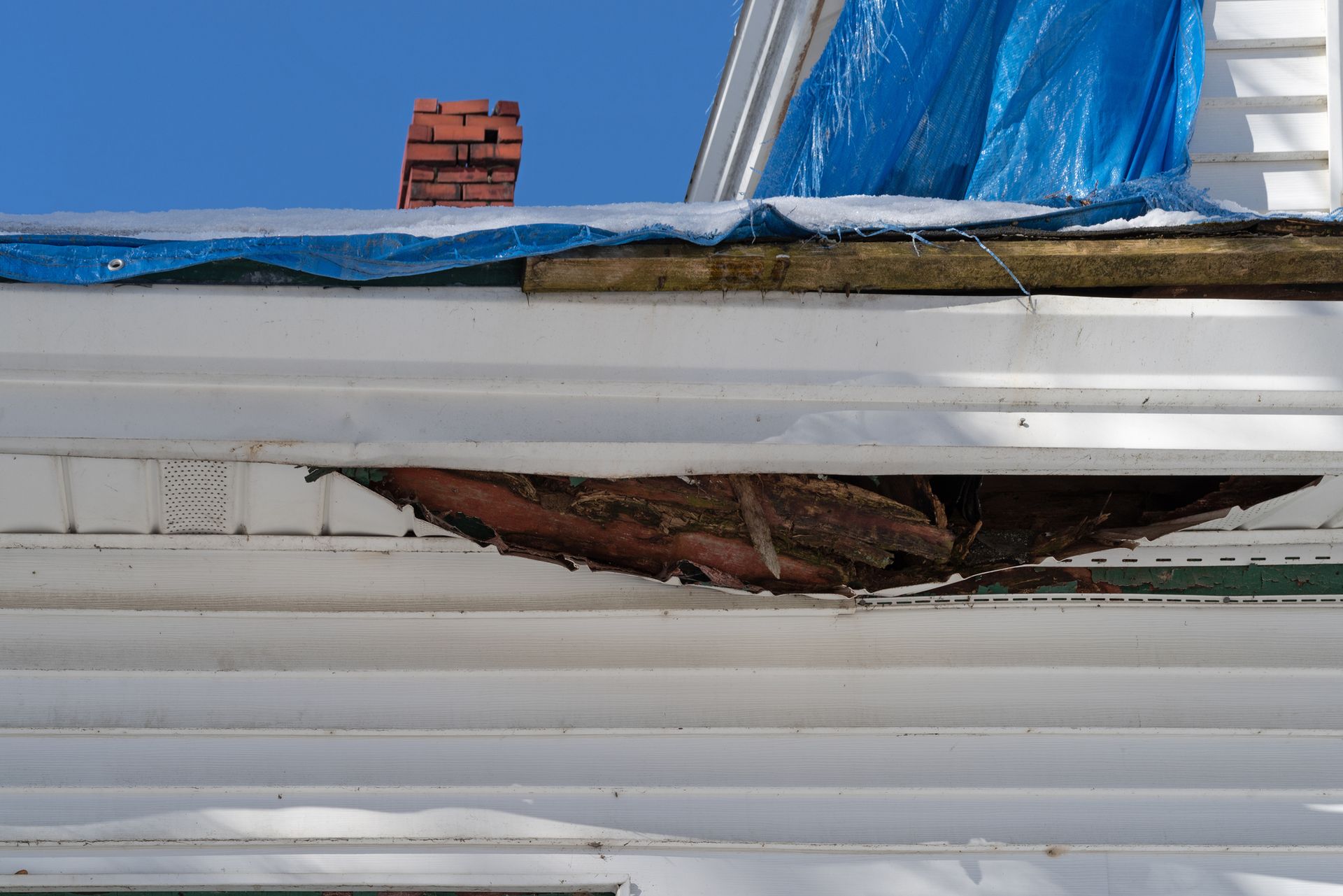 A blue tarp is covering the roof of a house.