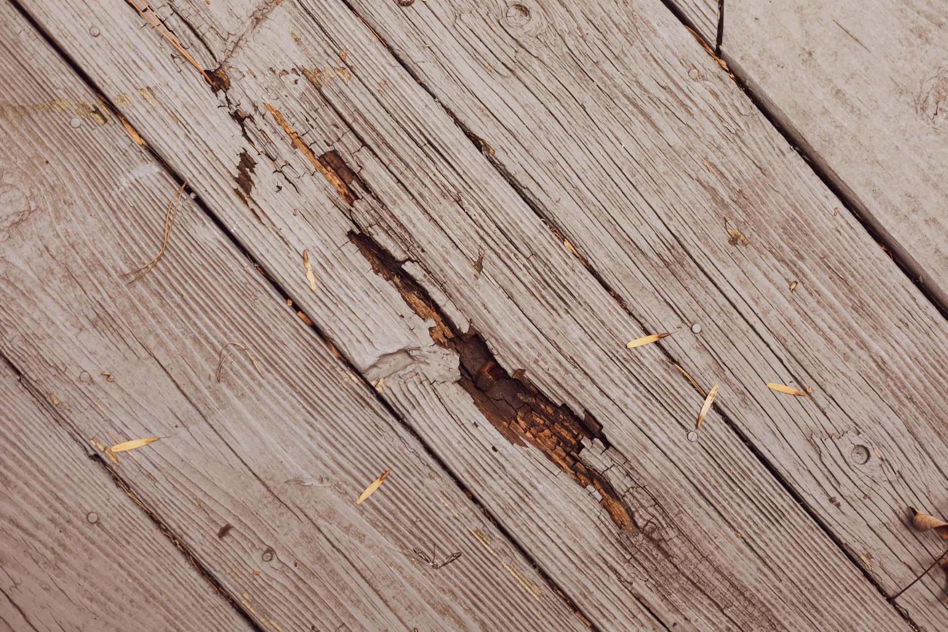 A close up of a wooden deck with a hole in it.