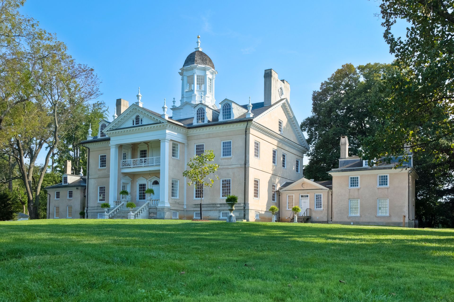 A large building with a dome on top of it is sitting on top of a grassy hill.