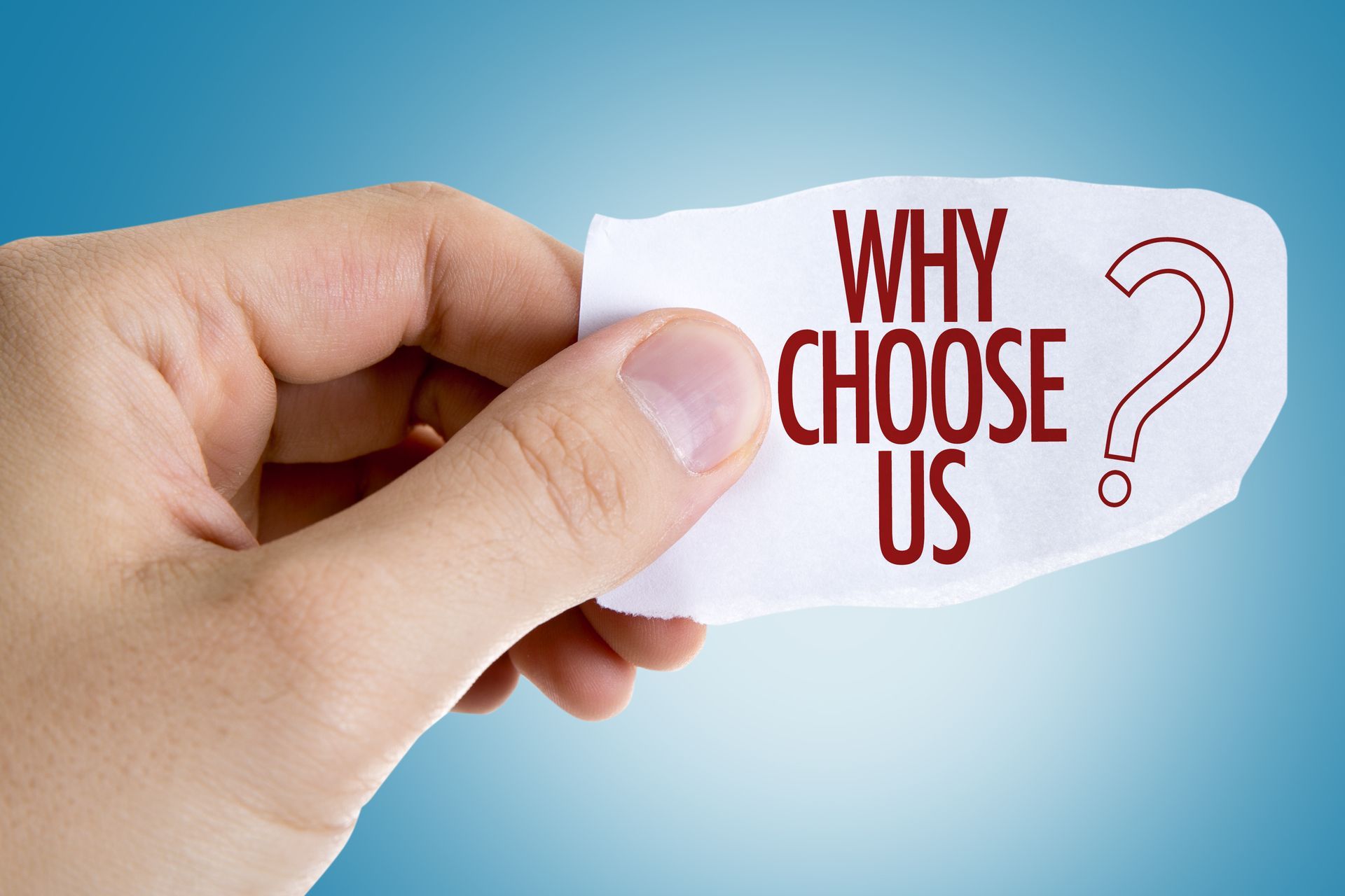 A hand is holding a piece of paper with the words `` why choose us '' written on it.