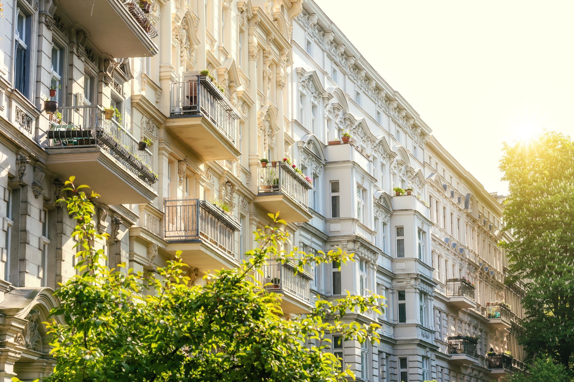 A large apartment building with balconies and trees in front of it.