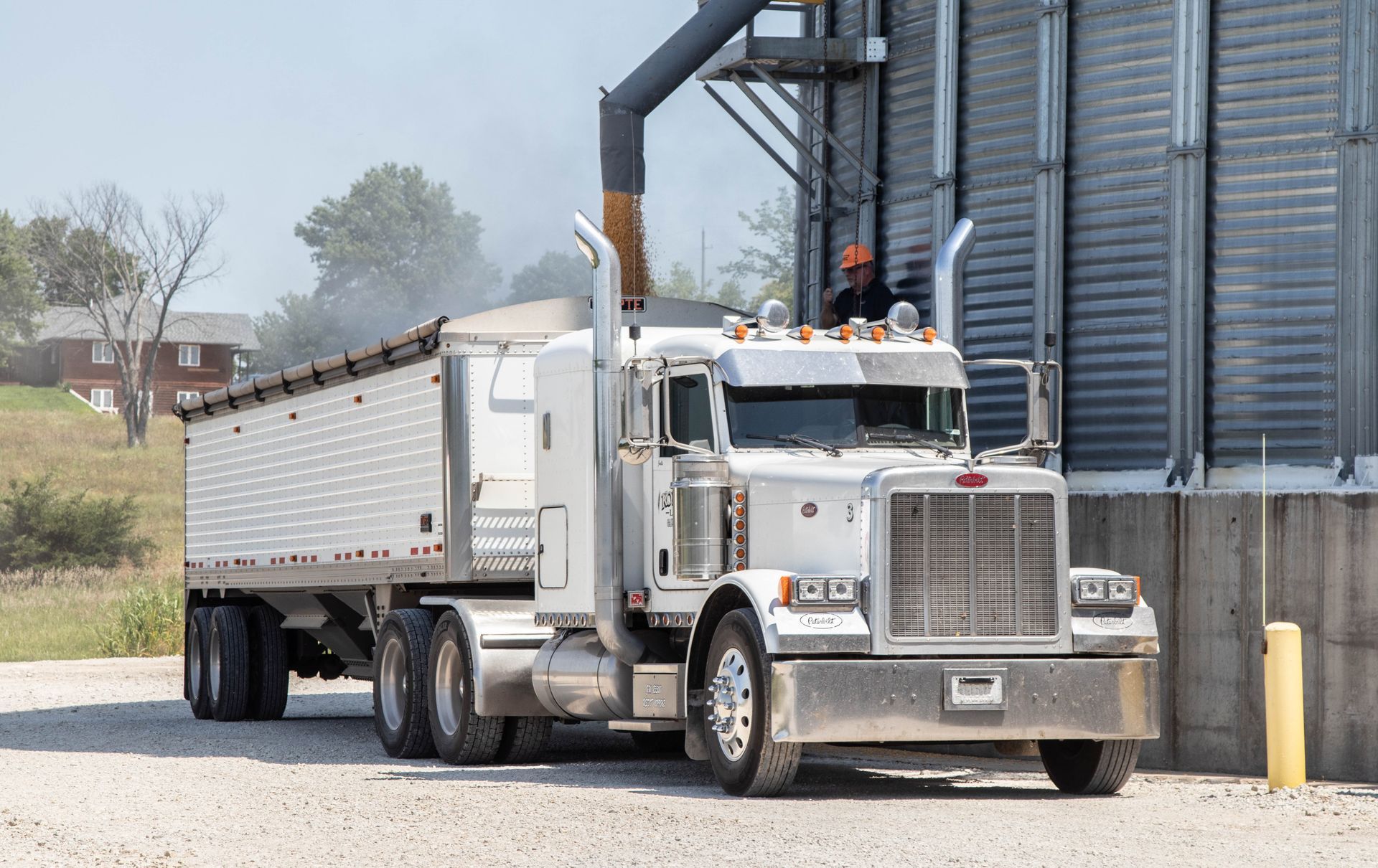 A semi truck with a trailer attached to it is parked in front of a building.
