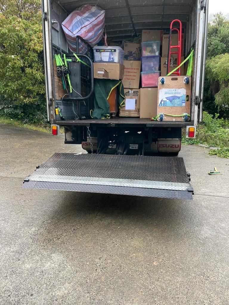 The back of a moving truck filled with boxes and a dolly.