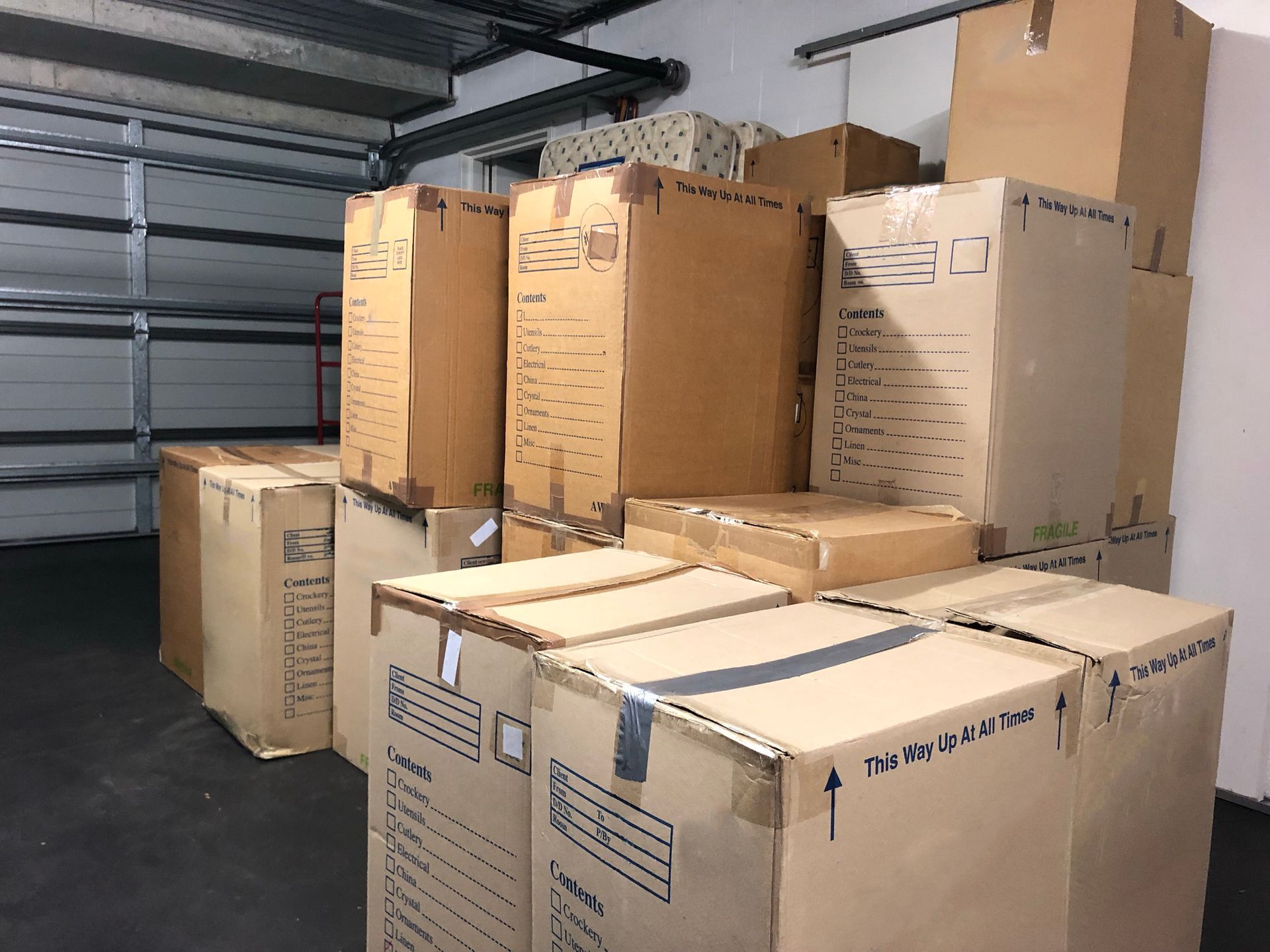 A bunch of cardboard boxes are stacked on top of each other in a garage.