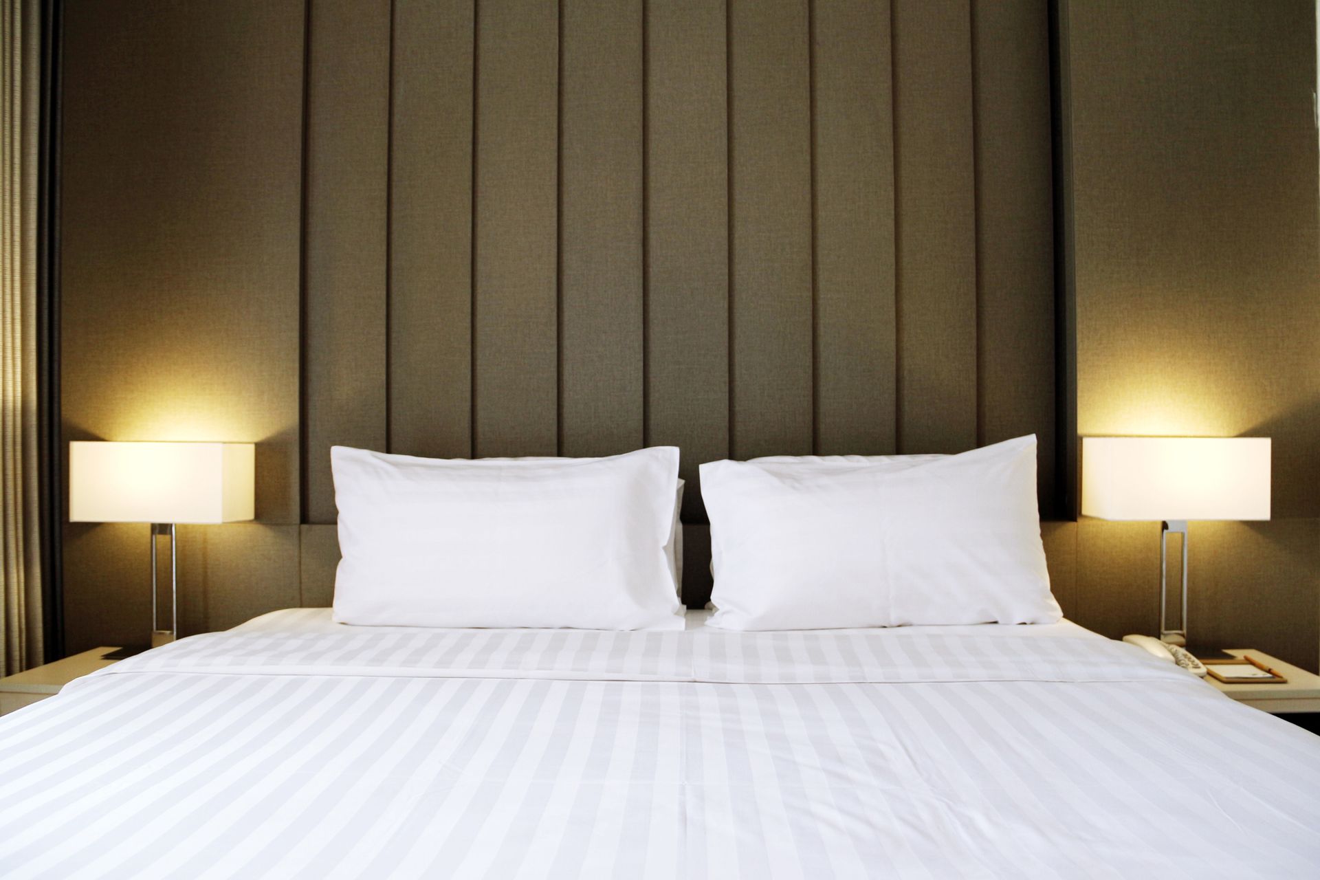 A bed with white sheets and pillows in a hotel room
