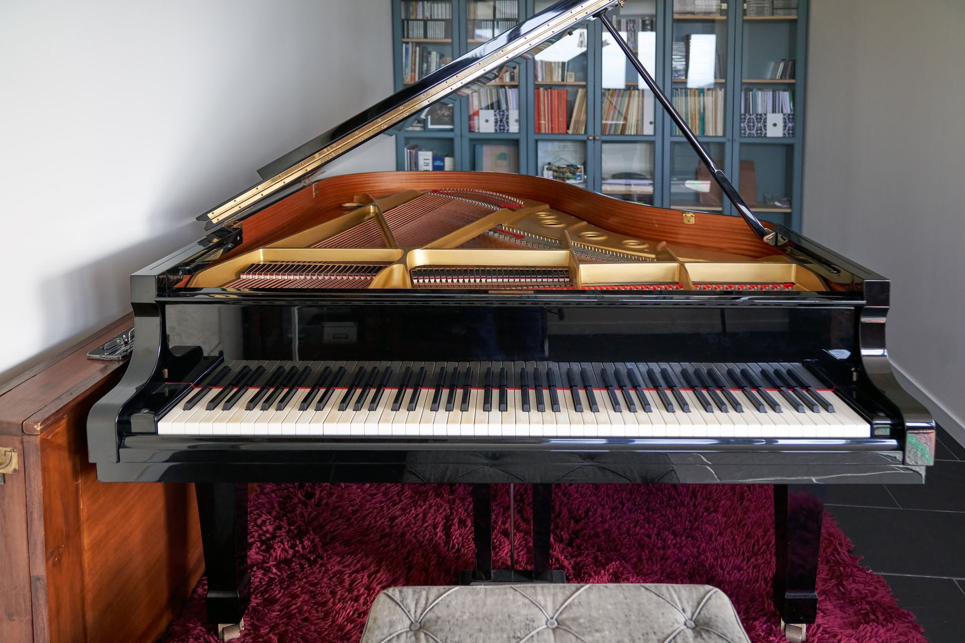 A grand piano is sitting on a purple rug in a living room.