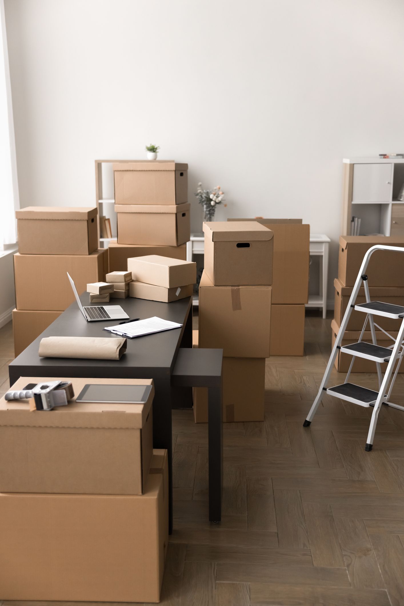 A room filled with lots of cardboard boxes and a laptop on a table.