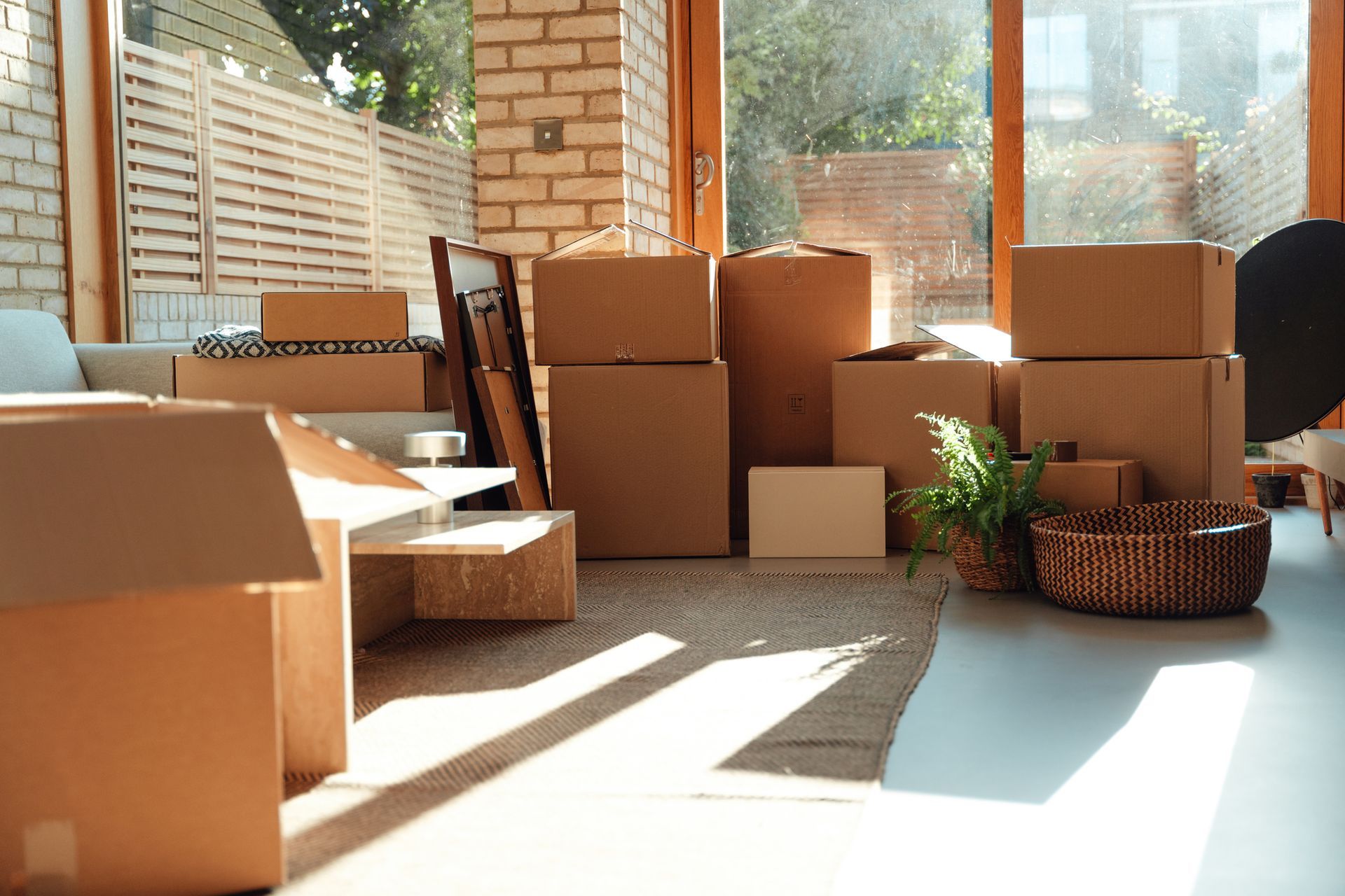 A living room filled with cardboard boxes and a basket.