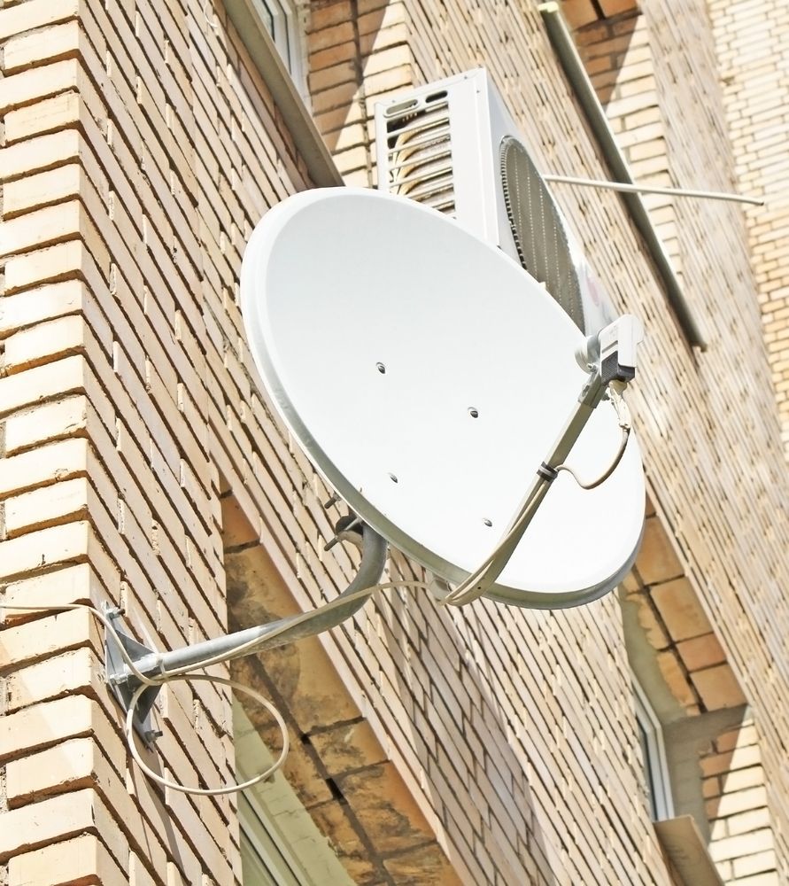 A Satellite Dish Is Mounted On The Side Of A Brick Building — Joytech In Ciccone, NT