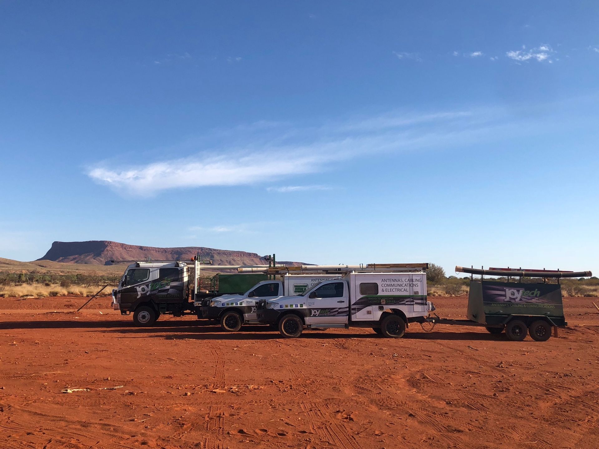 Three Trucks Are Parked In A Dirt Field With A Mountain In The Background — Joytech In Ciccone, NT