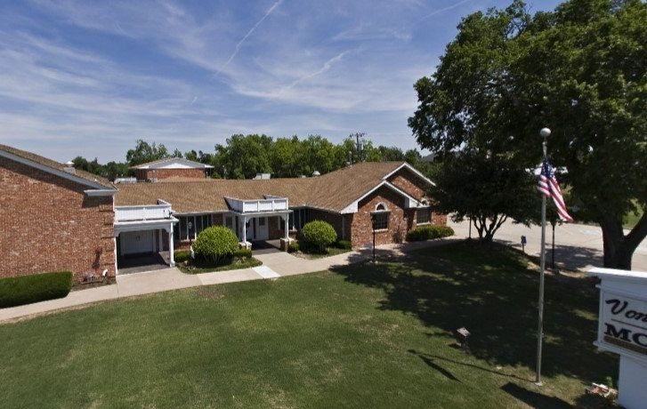 A large white building with a brown roof and a lot of windows.