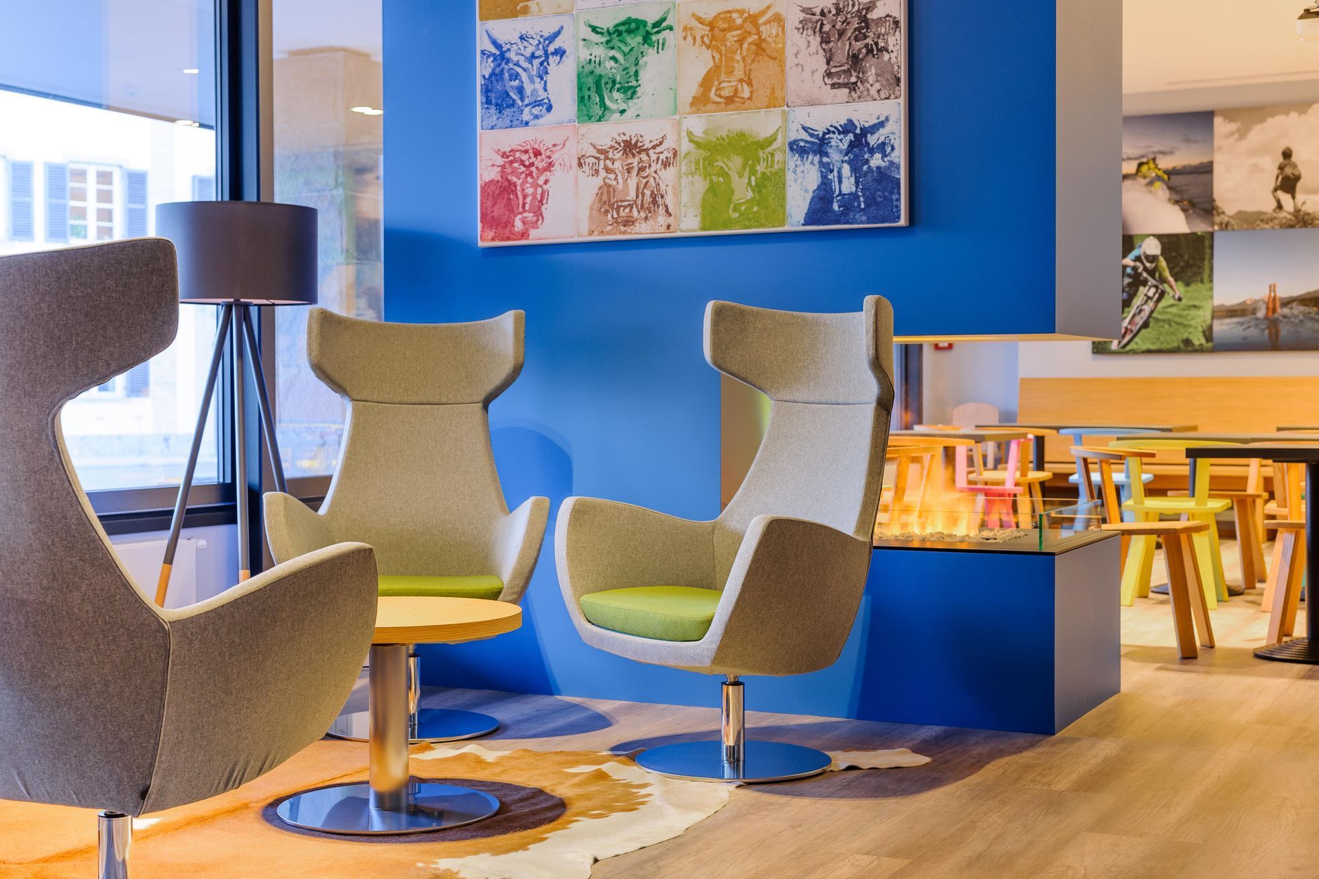 Moderne Bürolounge mit grauen Stühlen, blauen Wänden, Stehlampe und farbenfroher Wandkunst