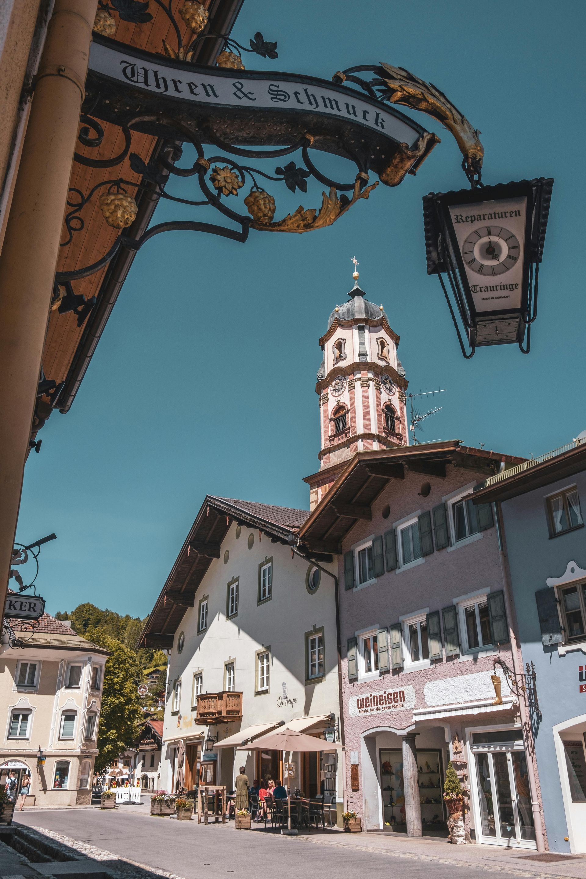 Sonnige europäische Stadtstraße mit farbenfrohen Gebäuden und einem Kirchturm vor blauem Himmel