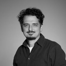Uma foto em preto e branco de um homem com cabelo cacheado e barba.
