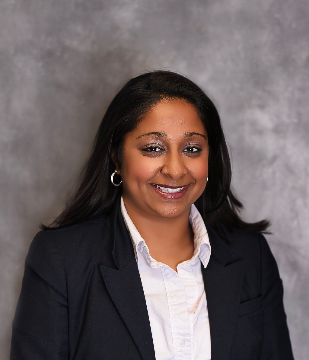 A woman in a black jacket and white shirt smiles for the camera