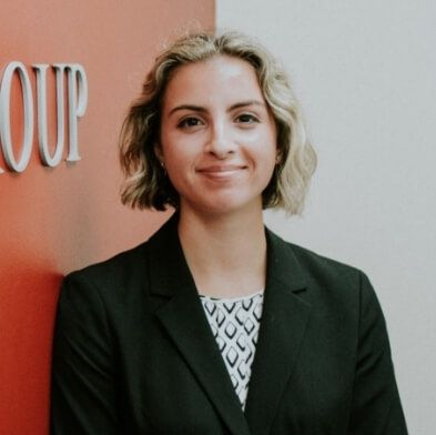 A woman in a suit is standing in front of a sign that says group