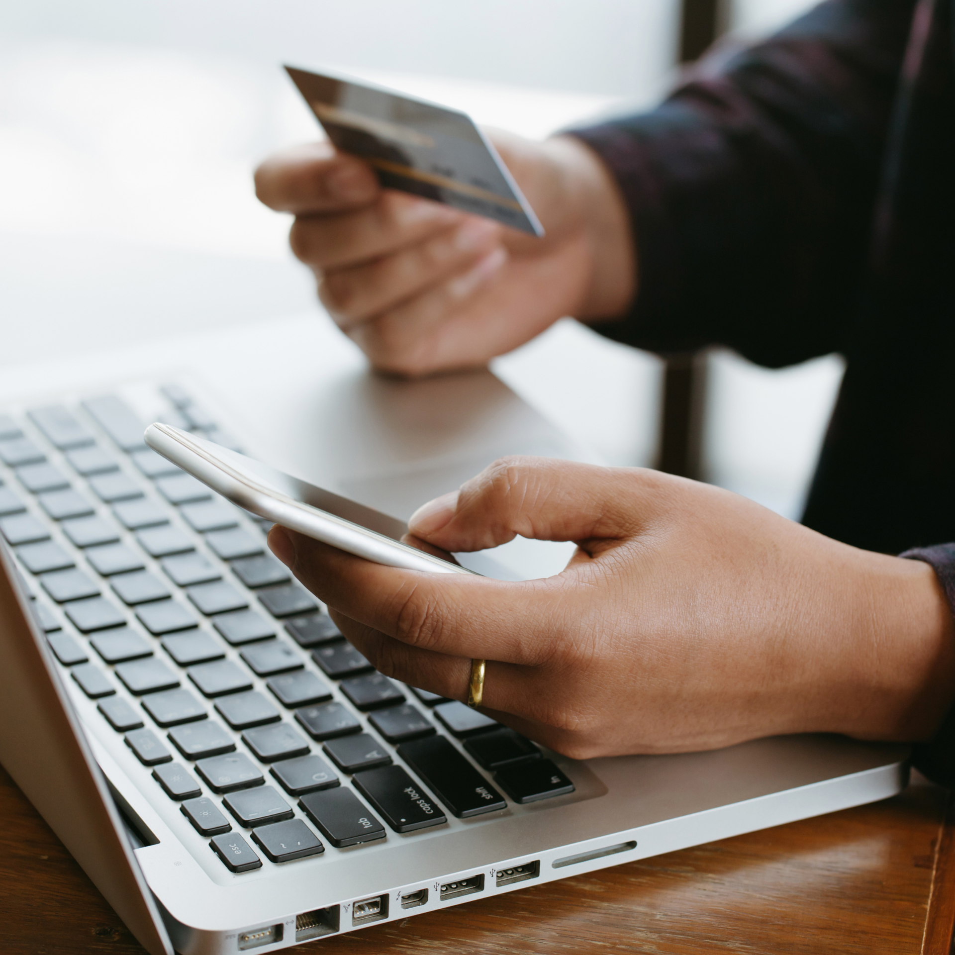 Durango HVAC Services - Person using a laptop, holding a credit card and smartphone for online payment.