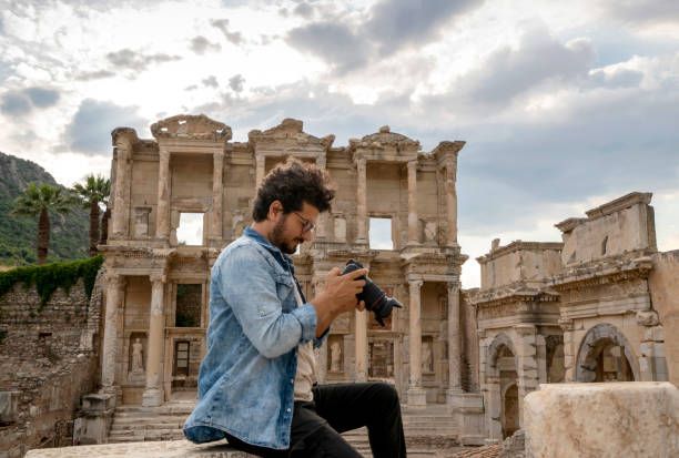 A photographer man looks at his camera in front of the Ephesus Celcus Library