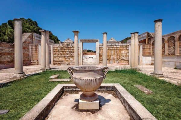 Ancient ruins with a large stone basin in the center, surrounded by columns