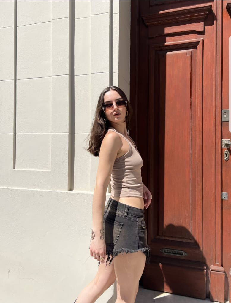 Shorts de mezclilla negros con bordes deshilachados y lavado desgastado sobre una superficie de baldosas.