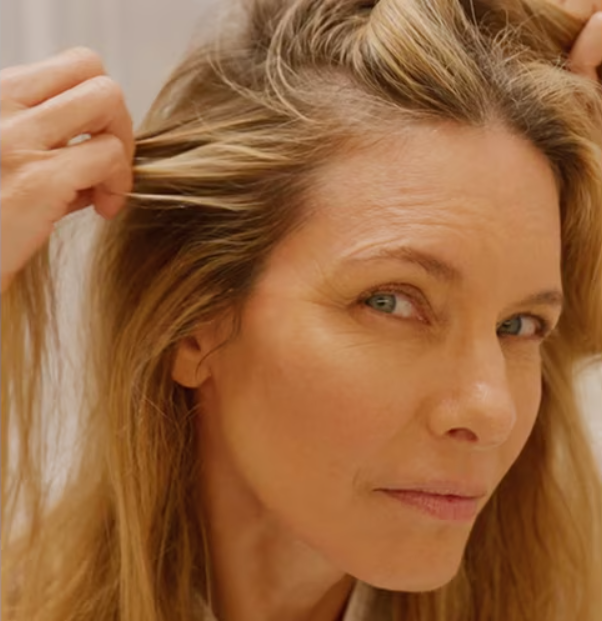 Close up of a woman examining her scalp and hair, showing natural texture and root area.