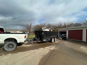 A white truck is towing a black dump trailer.