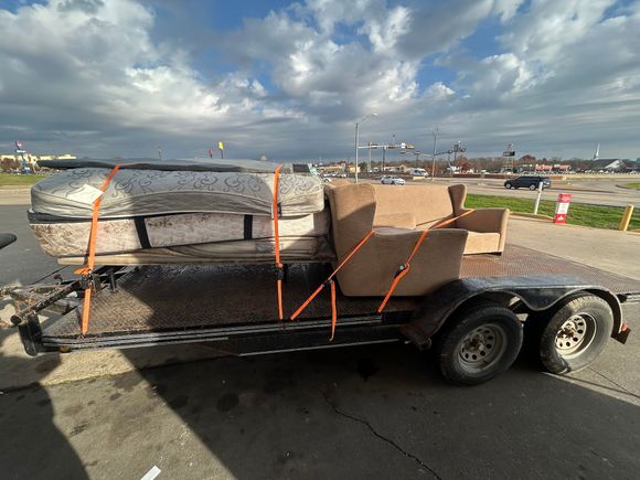 A trailer with a couch and a mattress on it.