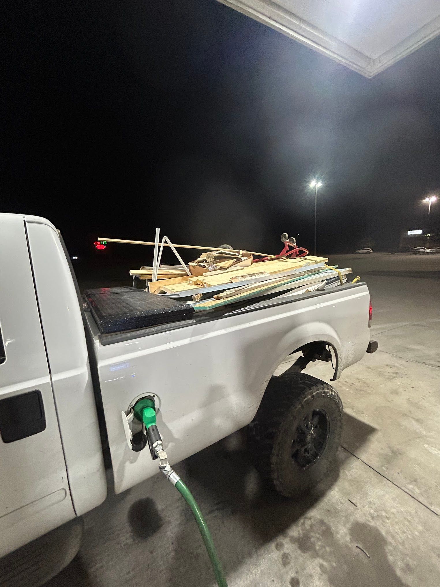 A white truck is being filled with gas at a gas station at night.