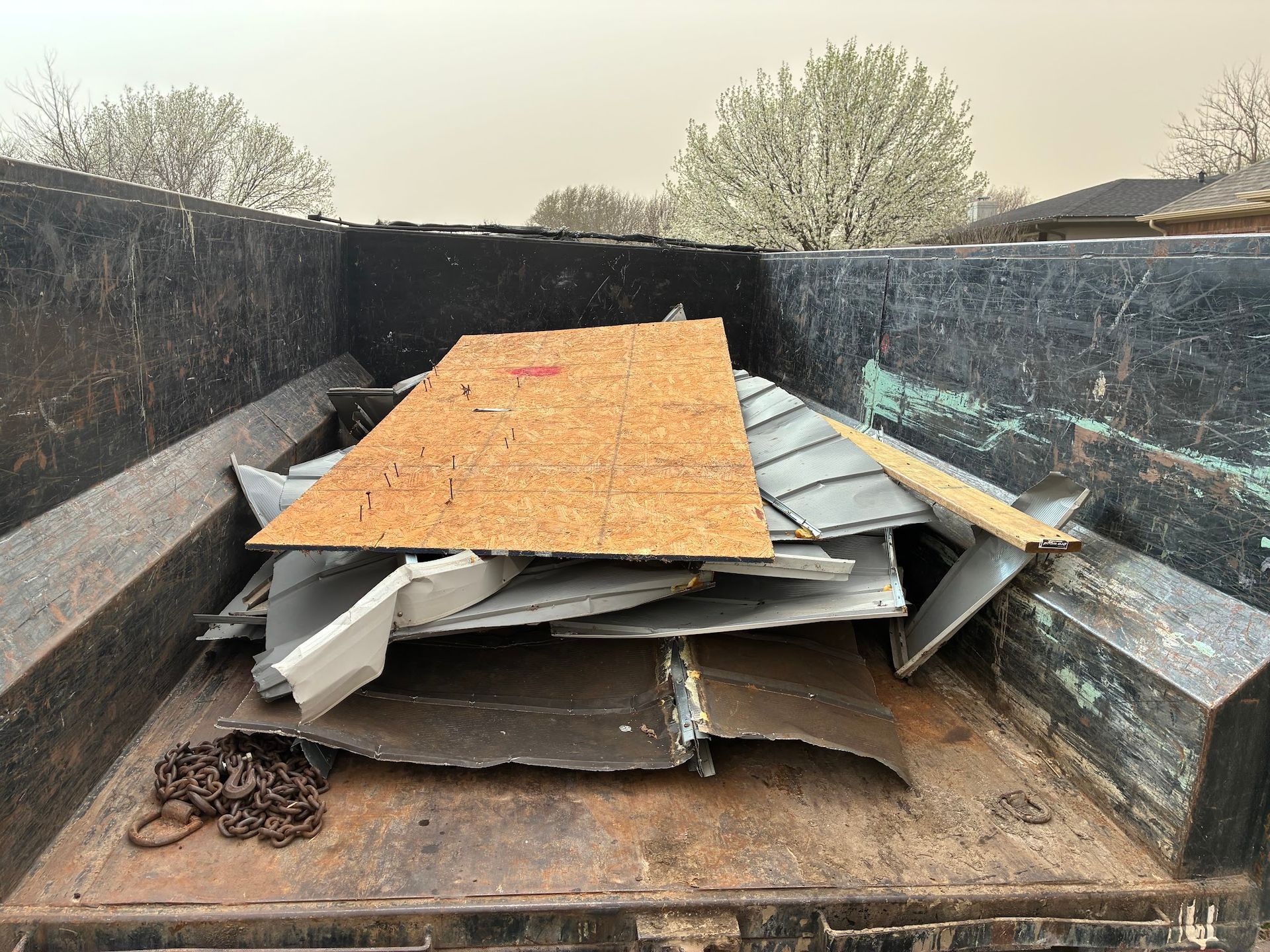 A dumpster filled with a pile of metal and wood.