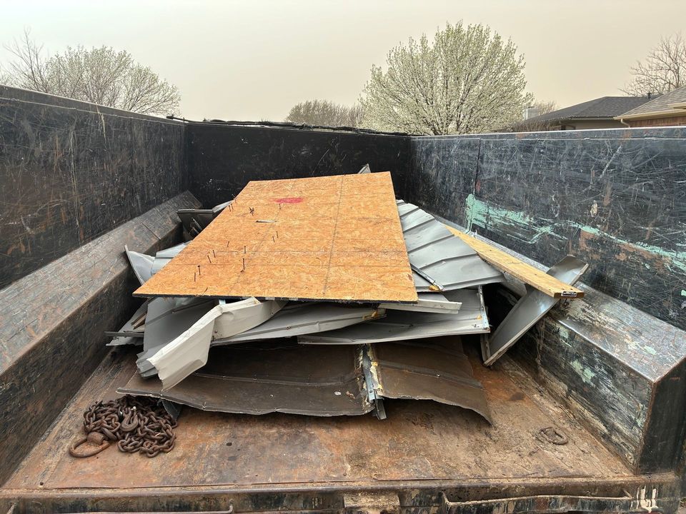 A dumpster filled with a pile of metal and wood.