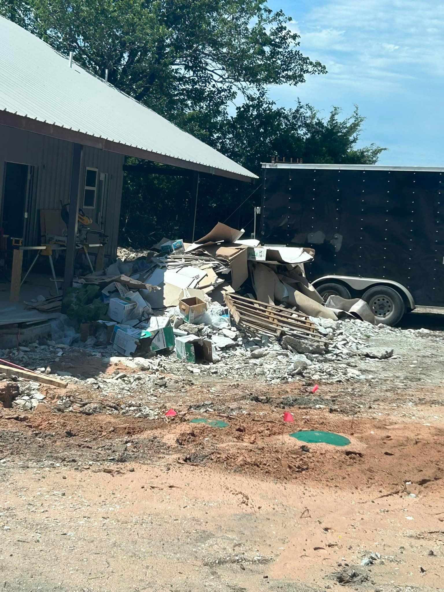 A black trailer is parked in front of a pile of trash.