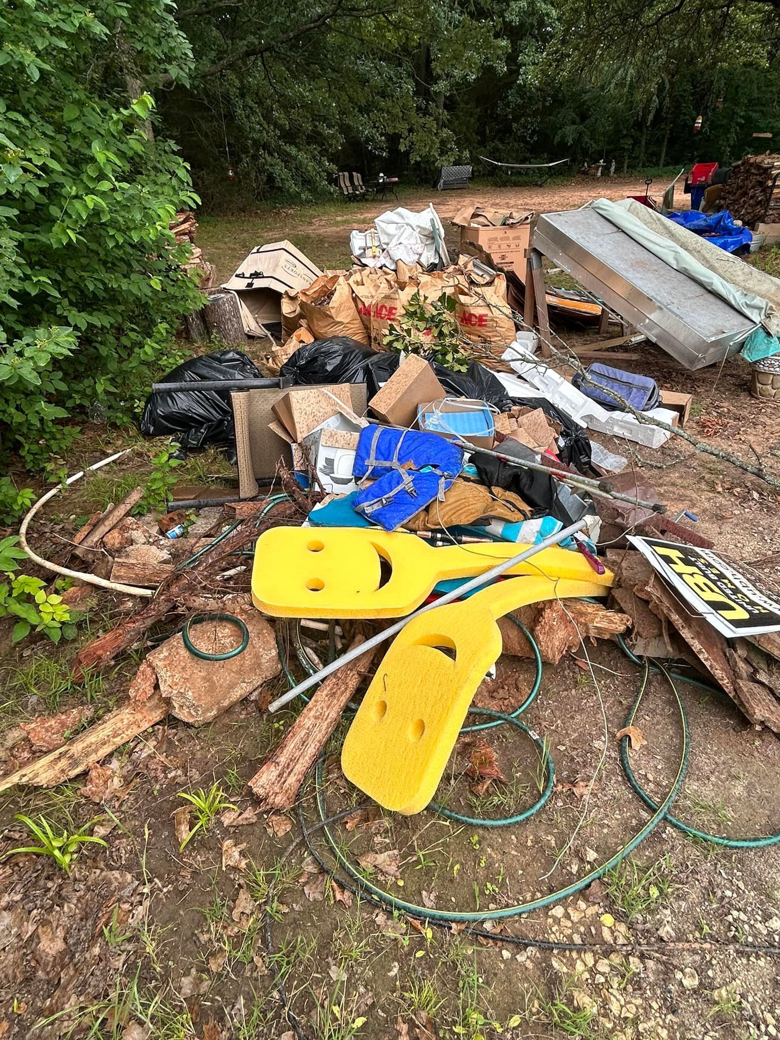 A pile of trash is sitting on the ground in a yard.