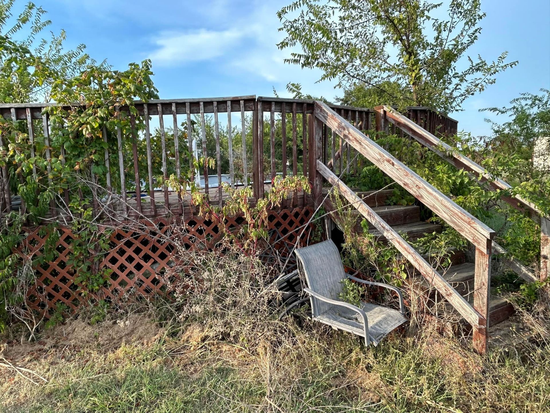A chair is sitting in the grass next to a wooden deck.
