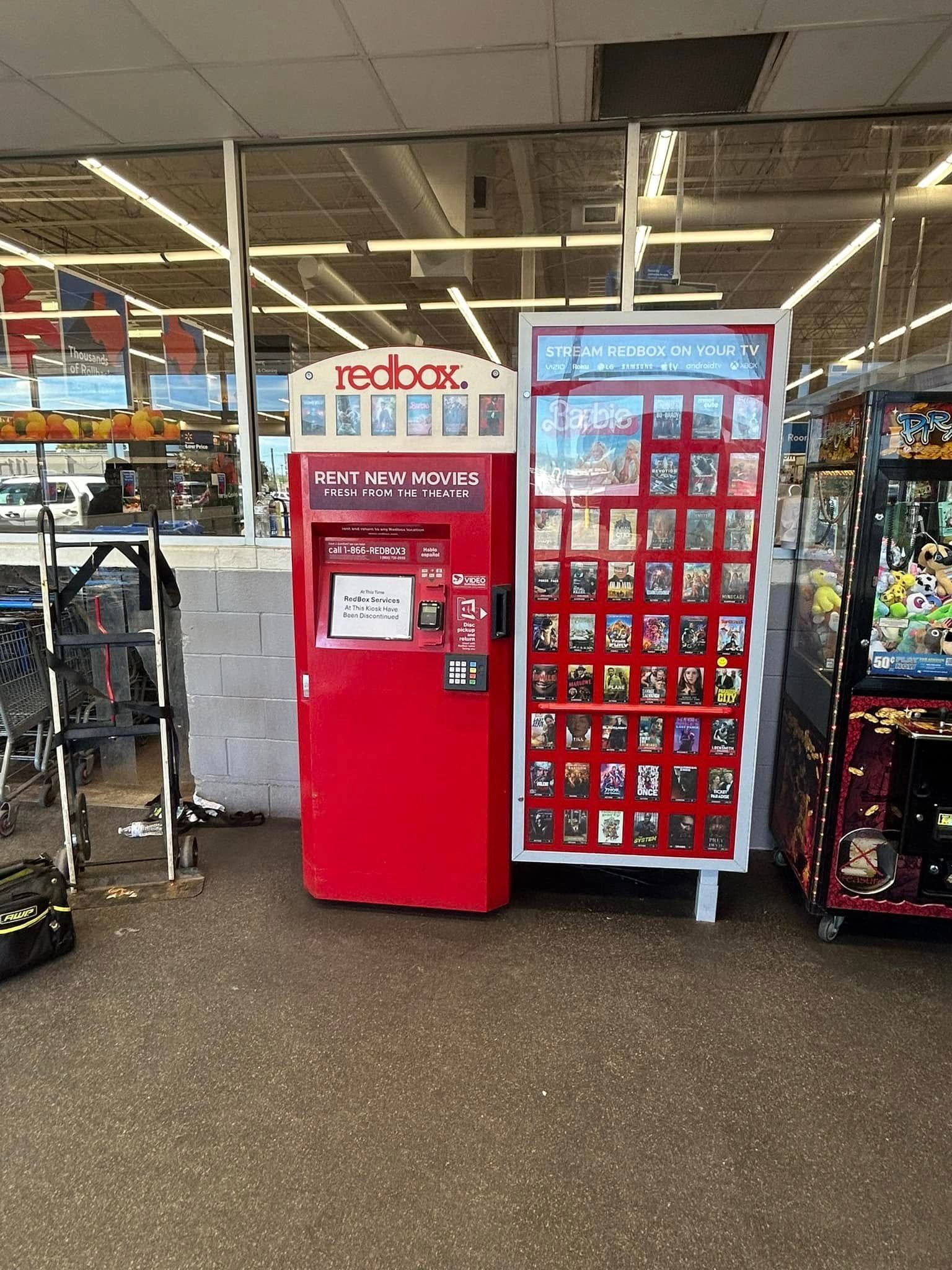 A red vending machine is sitting in the middle of a store.