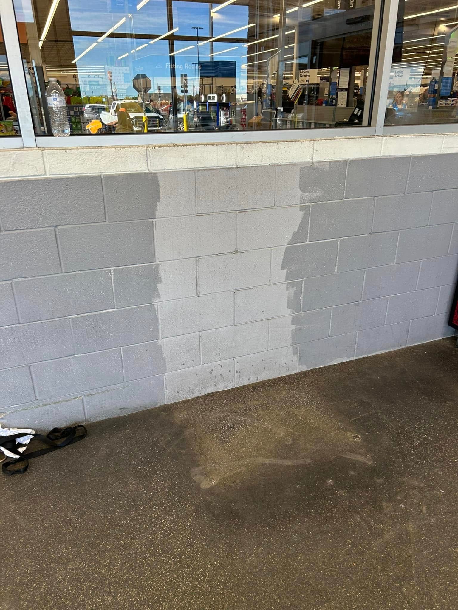 A brick wall is being painted white in front of a store.