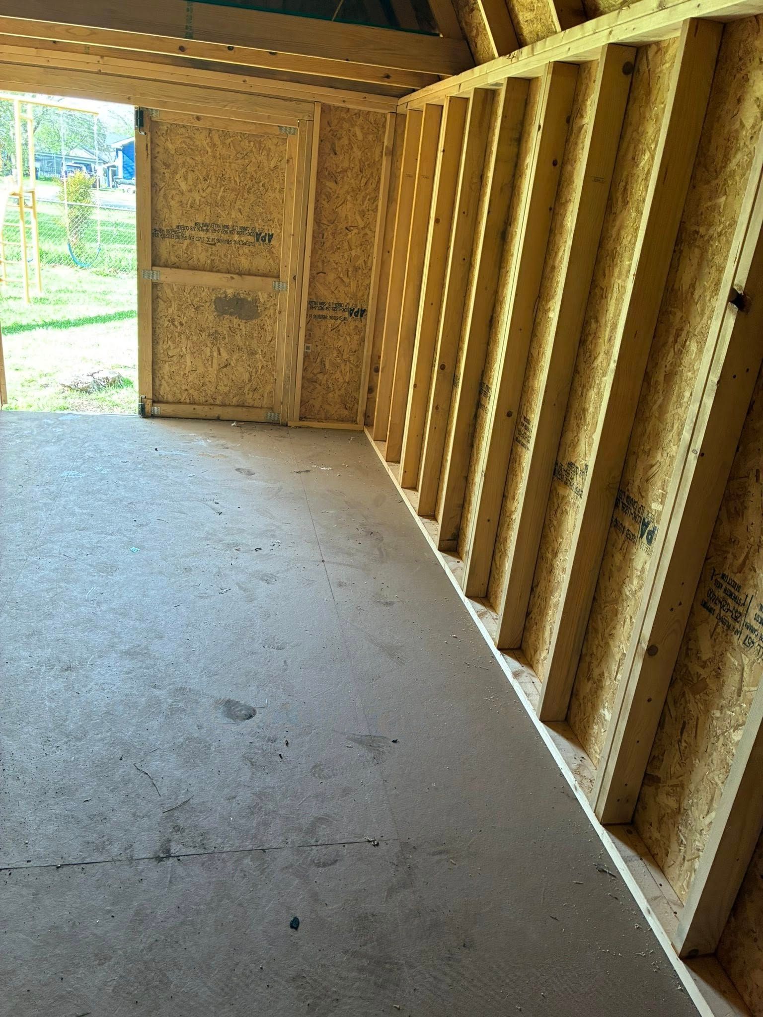 An empty room with wooden walls and a door that is open.