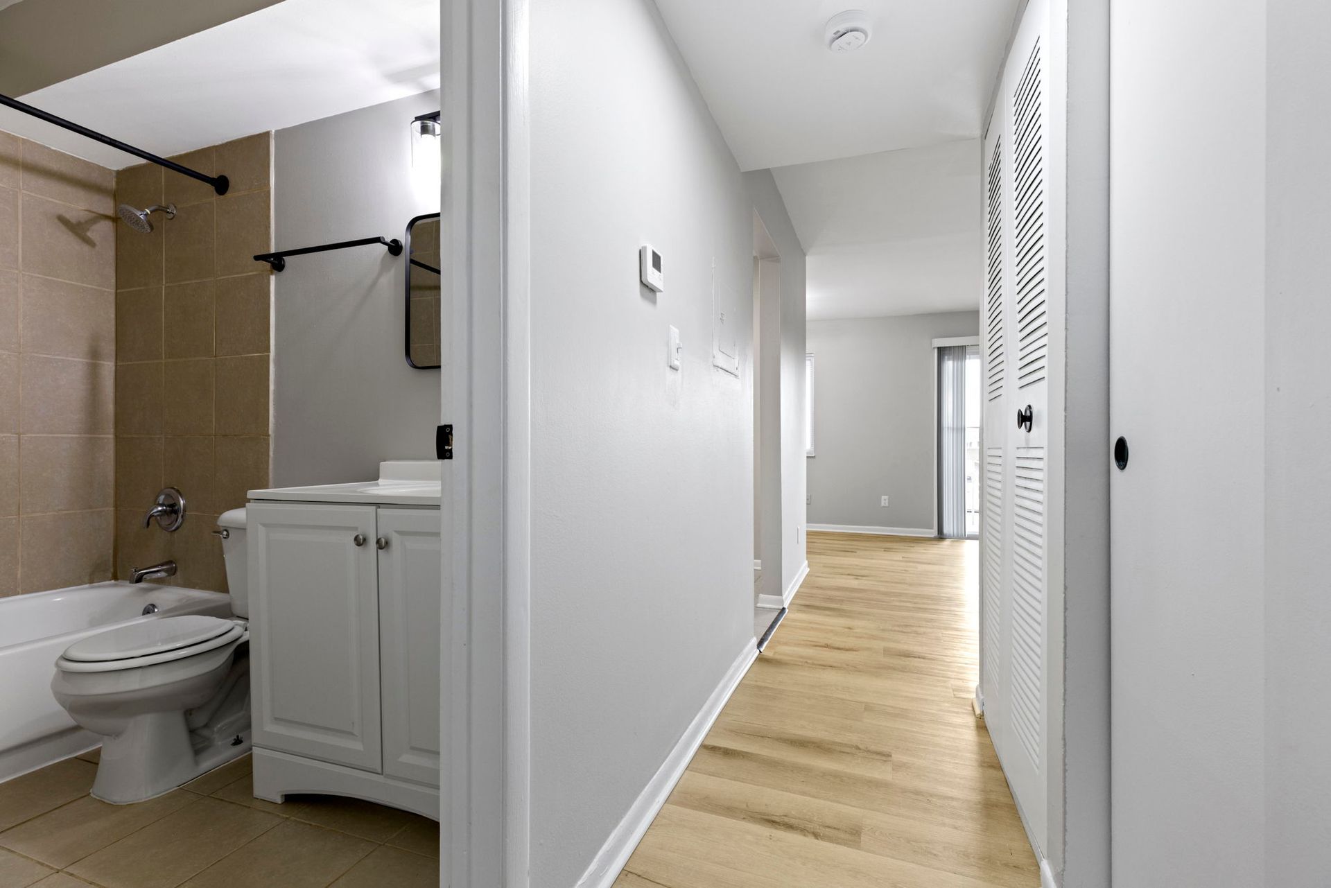 Bathroom and hallway with light wood floors and white walls.